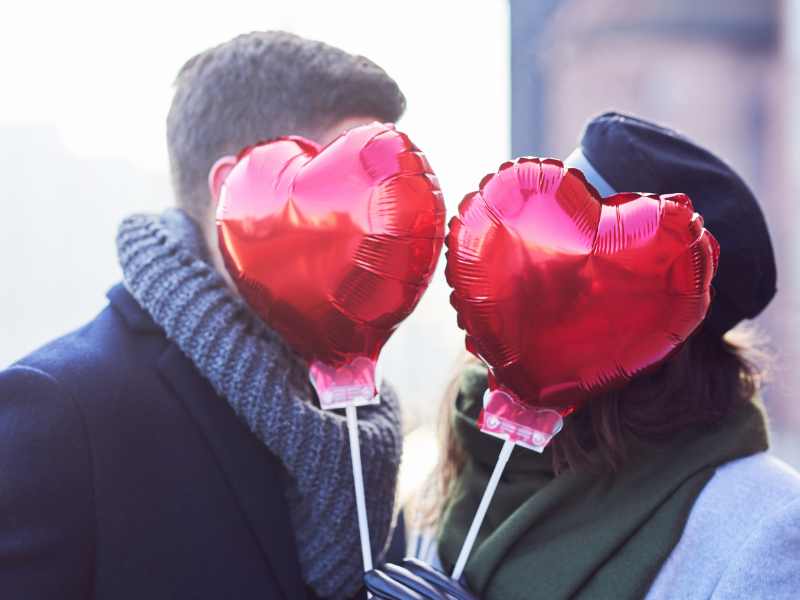 Couple hiding behind heart-shaped balloons