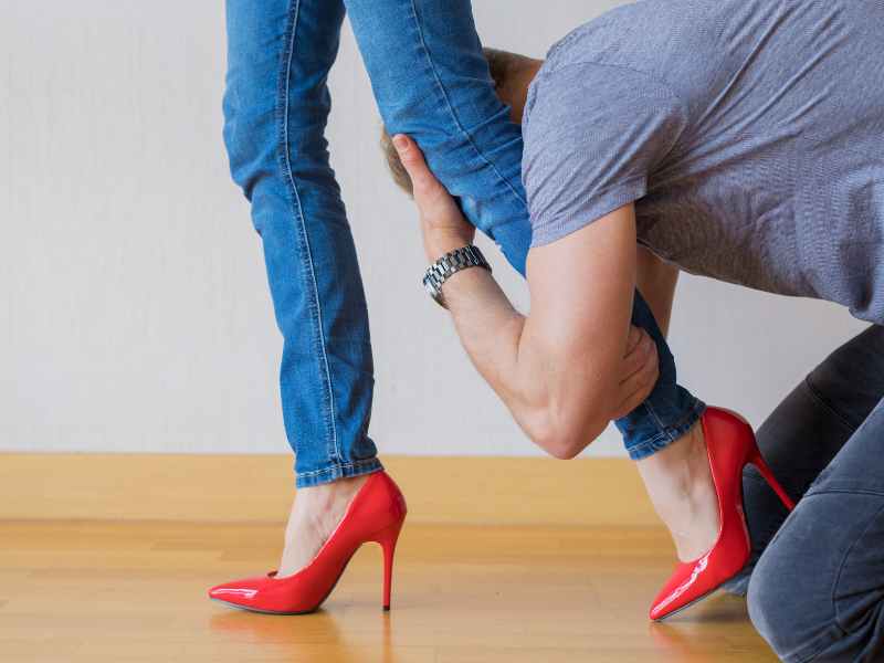 Man holding onto woman's legs as she walks away.